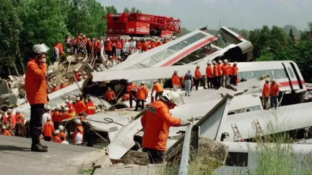 Rescue workers search for survivors after a high speed train slammed into an automobile that had plunged off a bridge onto tracks in Eschede, Lower Saxony, Germany, on 3 June 1998, with over 100 killed
