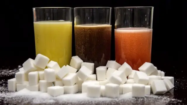 Carbonated drinks surrounded by sugar cubes