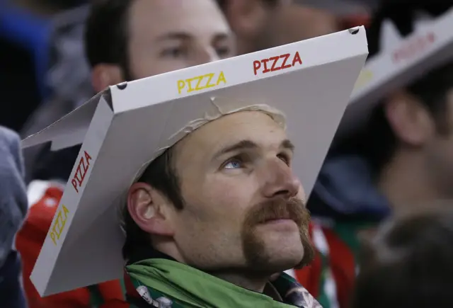 A fan with a pizza box on his head