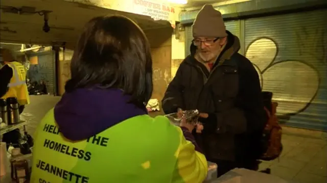 Homeless man getting food from volunteer