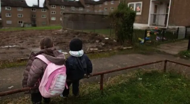 Two children sitting on a fence in deprived area