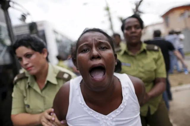 A member of the "Ladies in White" dissident group shouts as she is led away by police officers in Havana