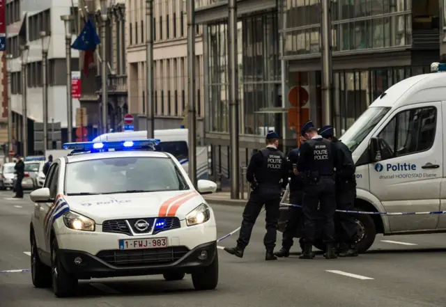 Policemen stand guard near a security perimeter set in the Rue de la Loi near the Maalbeek subway station, in Brussels, on March 22, 2016