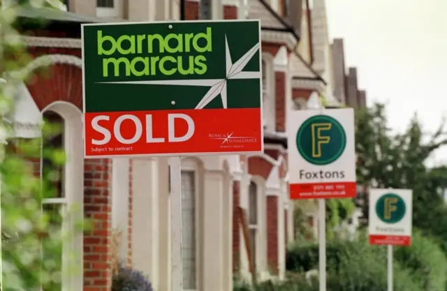 A row of houses with sold signs outside them