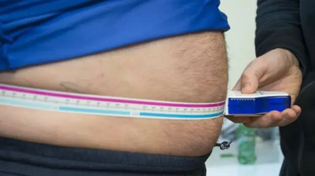 Overweight person has their waist measured