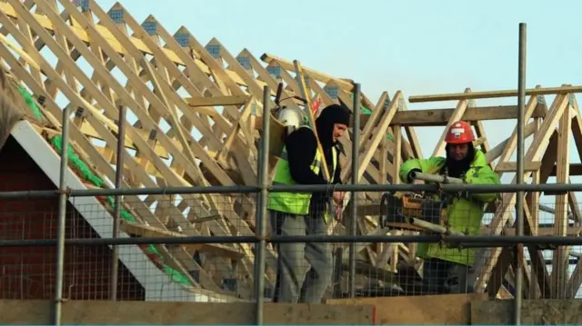 Two builders on the roof of a residential building site