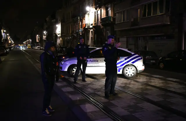 Police officers block a street as police make searches in Schaerbeek