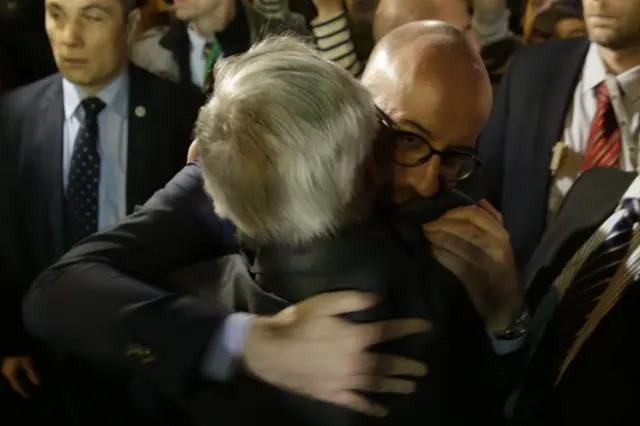 Belgian Prime Minister Charles Michel (r) embraces European Union Commission President Jean-Claude Juncker at a makeshift memorial at the Place de la Bourse in Brussels