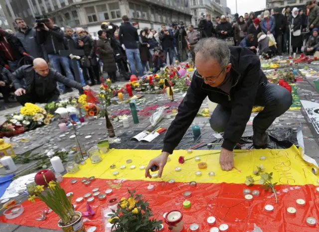 Men place a candles on a street memorial set up after the bomb attacks in Brussels