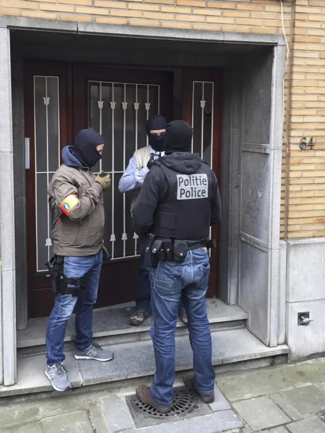 Masked Belgian police secure the entrance to a building in Anderlecht