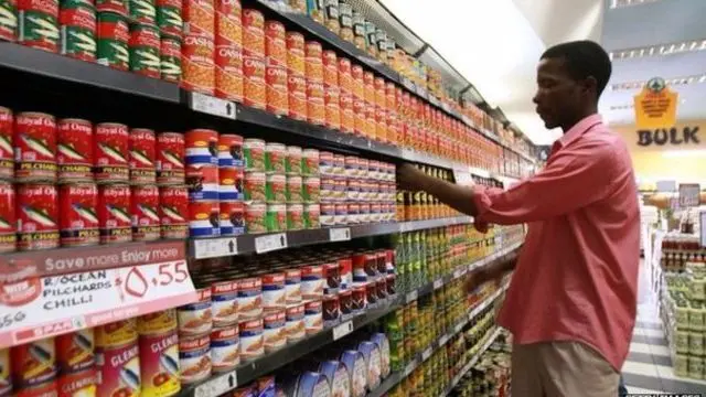 A shop worker arranging cans in a Harare supermarket