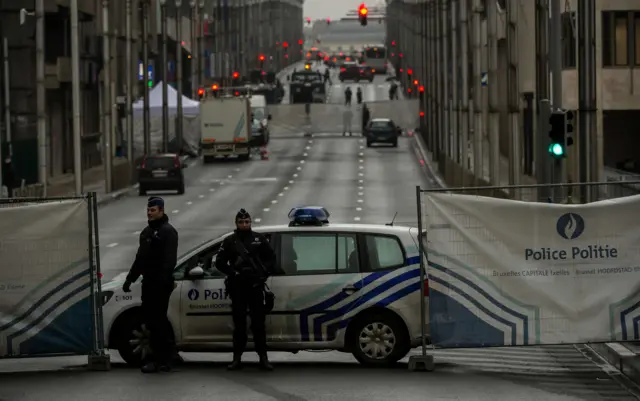 Policemen stand guard at the entrance of a security perimeter set around the Maalbeek metro station