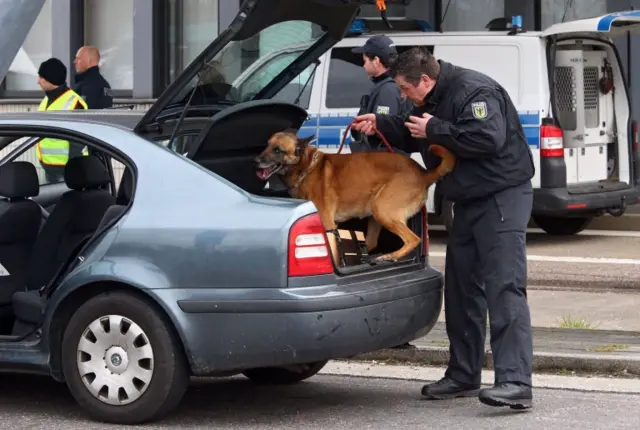 A German police officer searches the boot of a car at the border crossing in Lichtenbusch near Aachen, Germany