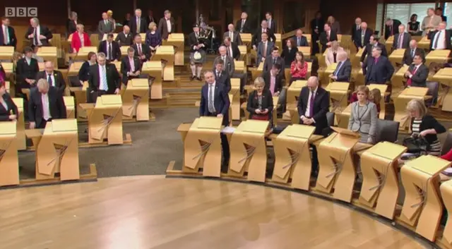 SNP MSP Stuart McMillan leads the MSPs playing the bagpipes