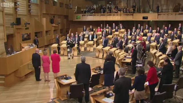 SNP MSP Stuart McMillan leads the MSPs playing the bagpipes