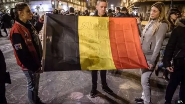 people holding Belgian flag in city after attacks