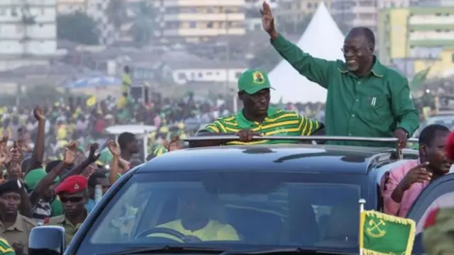 John Magufuli waves at supporters through this car sunroof