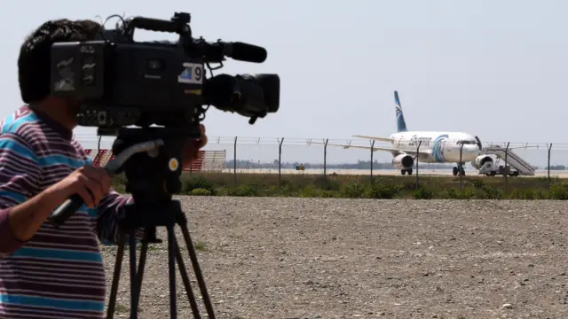 A cameraman takes footage of the hijacked EgyptAir A320 plane parked at a sealed-off area of the Larnaca Airport, in Larnaca, Cyprus, on 29 March 2016