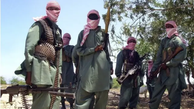 al-shabab members pose with weapons and faces covered