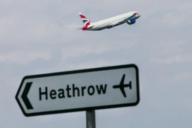 Plane flying above Heathrow sign
