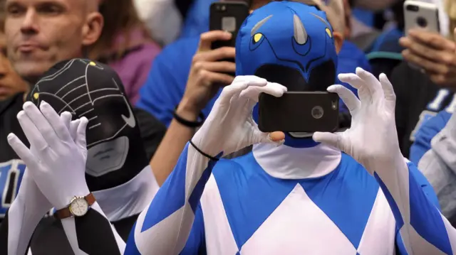 Fan dressed as a Power Ranger takes a picture during match