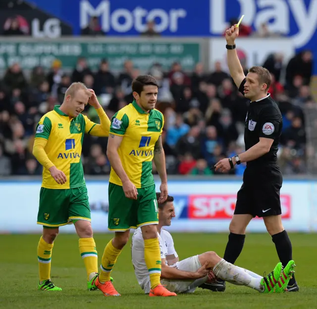 Referee Craig Pawson awards a yellow card