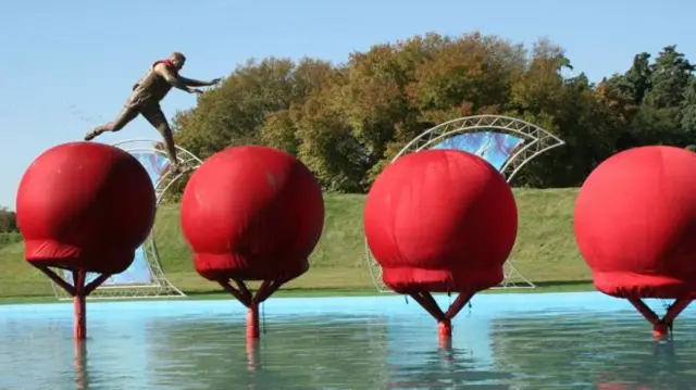 Man jumping across huge balloons