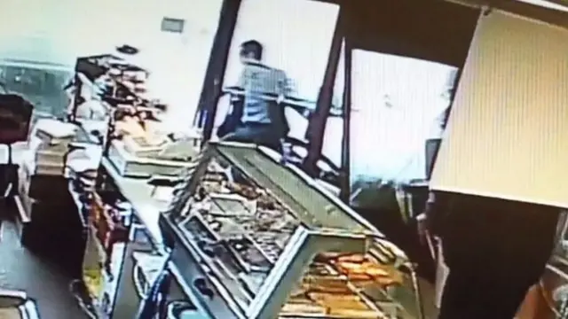 This is the moment a 42-year-old man leaps out of the way of a car, which strikes the bakery frontage.