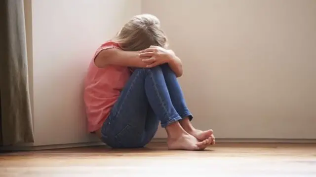 Child sitting in corner of a room