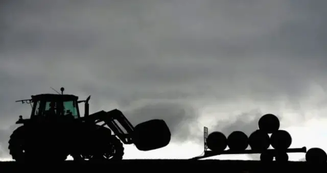 Tractor stacking hay bails