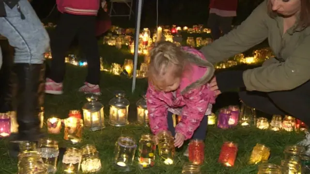 Candles in glass jars, with a little girl looking at one