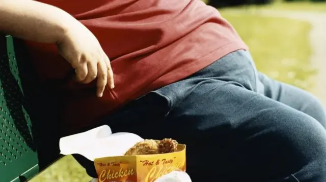 Man eating fried chicken on bench