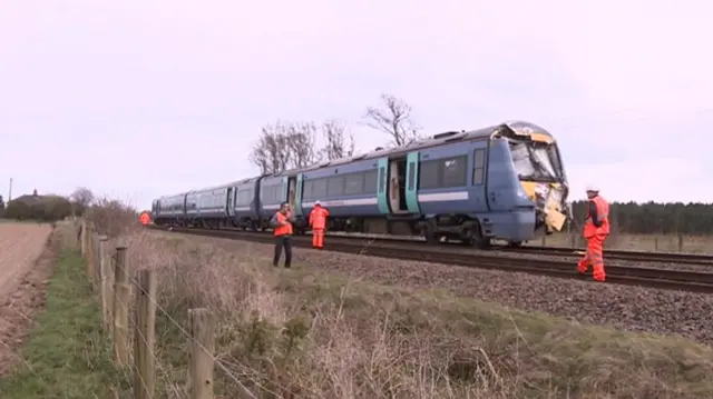 The train, with smashed front and emergency services