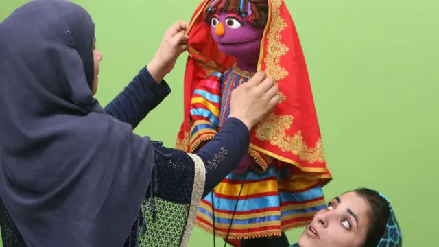 An Afghan puppeteer adjusts a scarf on Zari