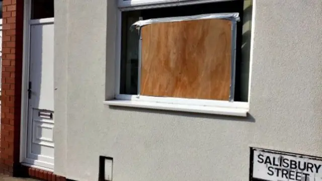 The boarded up front door and window at the Ahmed family's home in Salisbury Street, Tunstall