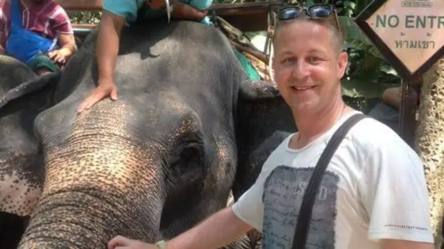 man stroking elephant trunk