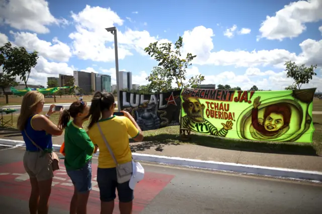 Women take photos of a banner supporting the impeachment of Dilma Rousseff