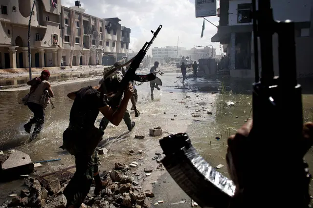 National Transitional Council (NTC) fighters take part in a street battle in the center of the city on October 14, 2011 in Sirte, Libya