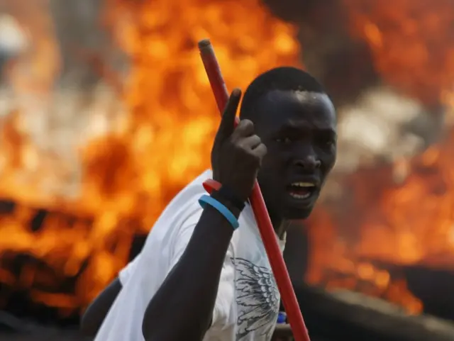 A protester stands in front of a burned barricade during a protest against Burundian President Pierre Nkurunziza's decision to run for a third term in Bujumbura, Burundi May 13, 2015