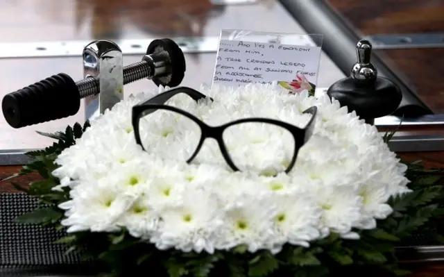 A pair of glasses rest on flowers at the funeral service of Ronnie Corbett,