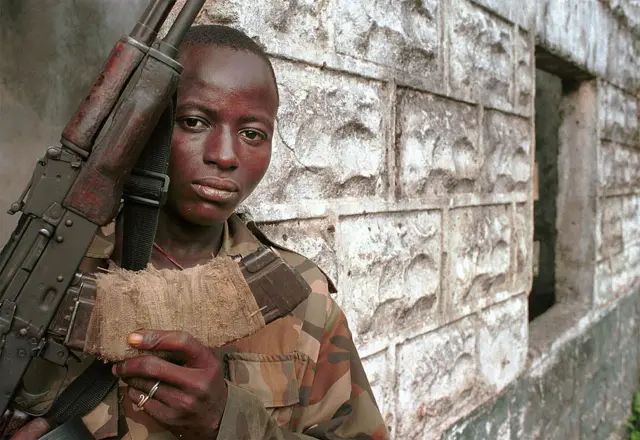 Henry, a teenaged Revolutionary United Force rebel solider, brandishes his weapon June 9, 2001 in the town of Koindu, Sierra Leone