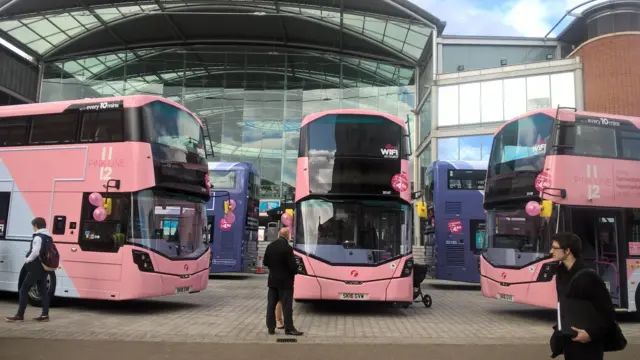 Five pink buses outside the Forum in Norwich