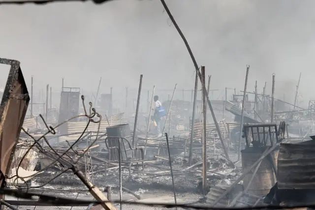 People walk among rubble in an United Nations base in the northeastern town of Malakal on February 18, 2016, where gunmen opened fire on civilians sheltering inside killing at least five people