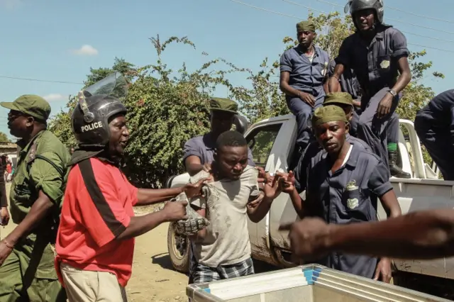 Zambian Police apprehend an alleged looter in the Zingalume Compound where residents have attacked broken and looted foreign-run shops in Lusaka on April 19, 2016