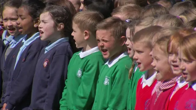 School children singing for the Queen