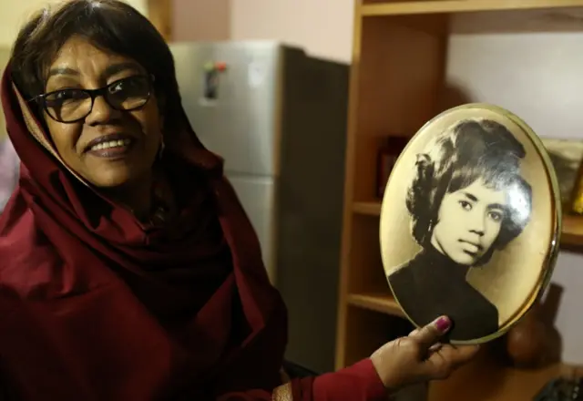 Amal Talsam holds a picture of herself when the band started in the early 1970s in Sudan