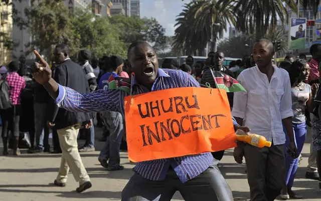 A supporter of Kenya's President Uhuru Kenyatta (poster), celebrates in the streets of Nairobi following the International Criminal Court's ruling to drop crimes against humanity charges against him, at the ICC courts at the Hague, on December 5, 2014.