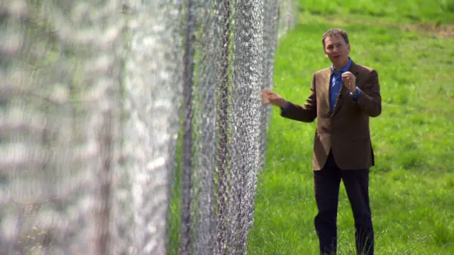 Mark Urban standing by a fence on the Austrian border
