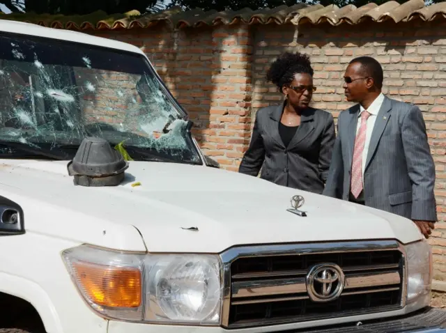 Burundian investigators stand next to the shrapnel-riddled vehicle in which Tutsi General and security advisor to Burundi"s vice president Athanase Kararuza was killed on April 25, 2016 in Bujumbura