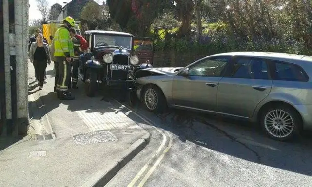 Firefighters at a road accident involving a vintage car